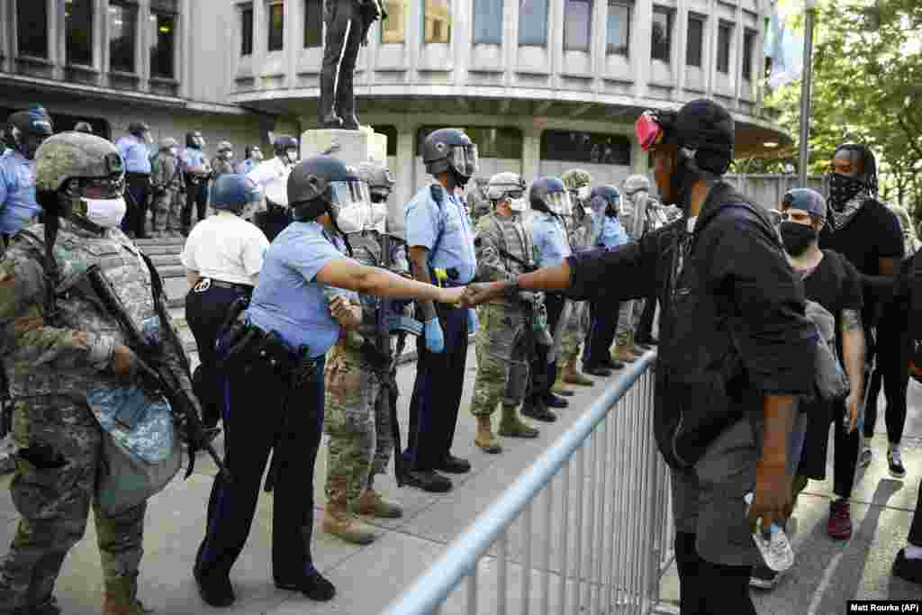 Prosvjednik i pripadnik policije izvode &quot;pozdrav pesnicama&quot; ispred policijske postaje u Philadelphiji, 1. lipnja.