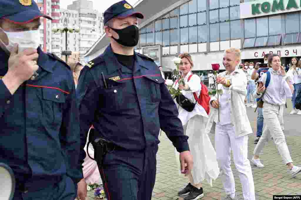 Protivladini demonstranti nude cvijeće dvojici policajaca u Minsku 12. augusta.