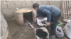 Un bărbat pune cărbune într-un cuptor în aer liber în Uzbekistan. (poză de arhivă)