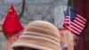 Një grua ec pranë flamurit kinez dhe atij amerikan, të ekspozuar pranë një dyqani në Pekin, më 31 janar 2025.