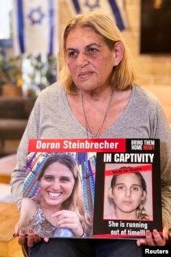 Simona Steinbrecher (64 de ani), în martie 2024, cu un afiș din campania Forumului Ostaticilor.