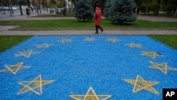 O femeie trece pe lângă o reprezentare a steagului Uniunii Europene, amplasată în Grădina Publică „Ștefan cel Mare” din centrul Chișinăului.