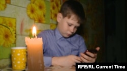 Egy orosz kisfiú készíti a házi feladatát áramszünet alatt