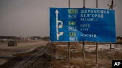 O mașină trece pe lângă un indicator rutier ciuruit de gloanțe și șrapnele pe drumul spre Belgorod, în apropiere de granița Ucrainei cu Rusia. (foto arhivă)