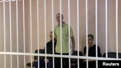 Британецот Ејден Аслин, Шон Пинер и Мароканецот Брахим Саудун во кафез во судница на локација наведена како Доњецк.
