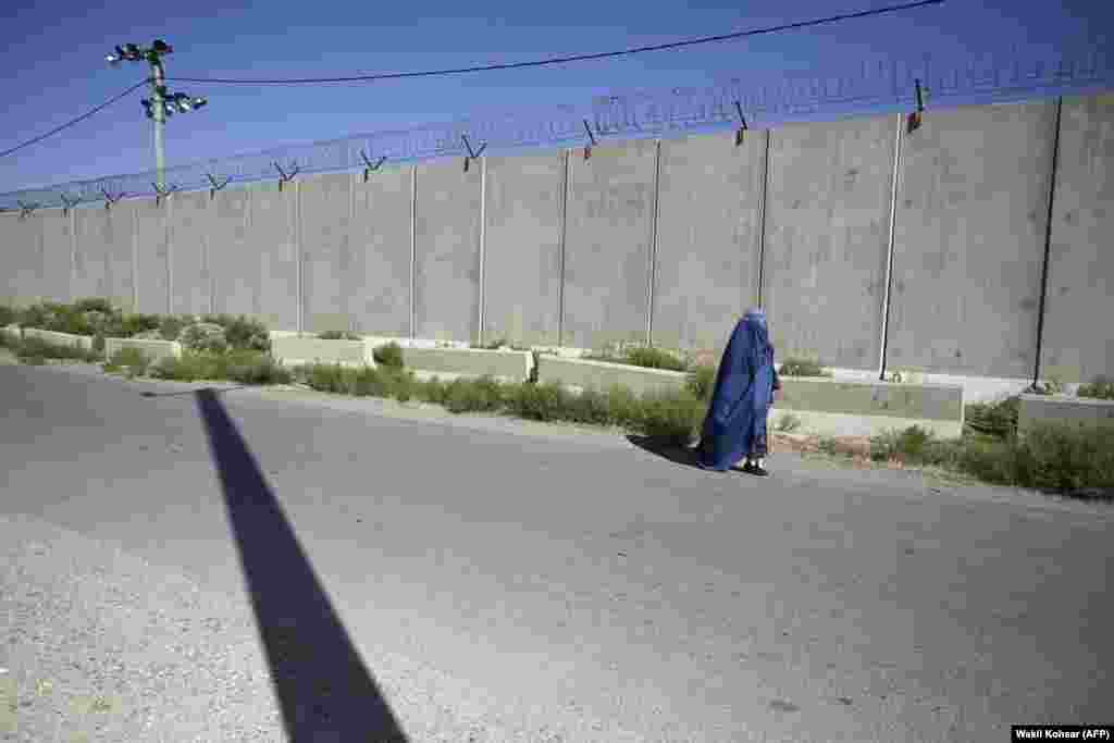 Një grua me burka më 1 korrik ecën pranë ish-bazës ushtarake amerikane në Bagram. Burkat janë veshje që mbulojnë të gjithë trupin dhe kanë një rrjet që mbulon fytyrën. Disa myslimanë fundamentalistë, që interpretojnë fragmente të diskutueshme të Kuranit, thonë se gratë duhet të mbulohen plotësisht kur dalin në publik.