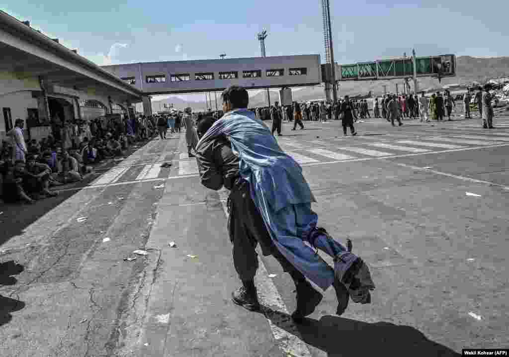 An injured man is carried among the crowds at the airport. 
