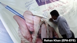 A Pakistani journalist signs a banner during a protest against the deteriorating security situation for journalists in the country in May 2018 (file photo).