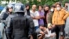 Zyrtarë policorë dhe migrantë afër një tende në Rudninkai, Lituani. 2 gusht 2021.