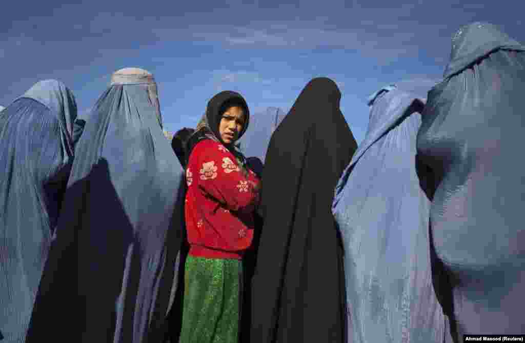 Një vajzë afgane duke qëndruar mes vejushave të veshura me burka, gjatë një projekti punësimi nga organizata humanitare &quot;CARE International&quot;. (Kabul, 6 janar 2010)