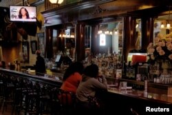 Urmărind la un bar Convenția Națională Democrată organizată virtual . Baza reuniunii este la Milwaukee, statul Wisconsin.