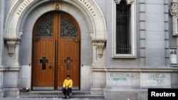 Spania -- Un cerșetor pe pragul unei biserici lângă un graffiti care spune: „Astăzi nici măcar Dumnezeu nu lucrează”.