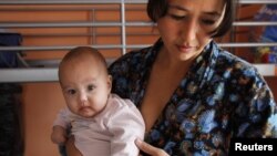 Täjigistanly durmuşa çykmadyk zenan özüniň ekiz çagalarynyň biri bilen Moskwada krizisdäki zenanlar üçin merkezde, 2011-nji ýylyň 16-njy oktýabry.
