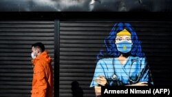 Një person kalon pranë një murali në Prishtinë dedikuar punëtorëve shëndetësorë, për luftën e tyre kundër pandemisë. 