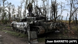 Militarii ucraineni inspectează un tanc rusesc capturat în timpul contraofensivei armatei ucrainene la periferia orașului Izium, regiunea Harkov, 11 septembrie 2022