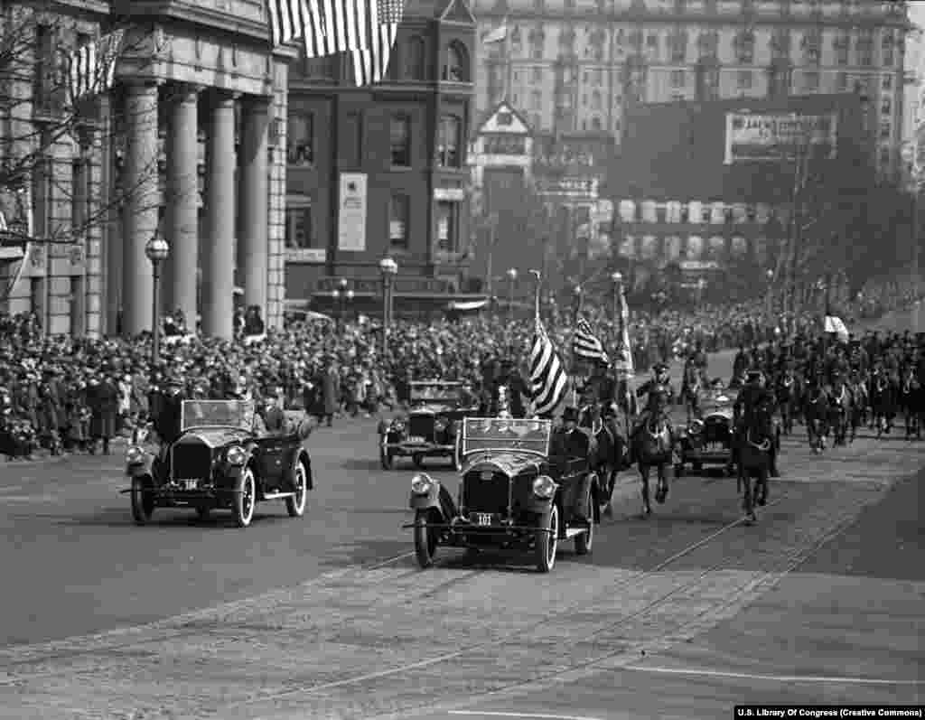 Cortegiul de mașini al președintelui Calvin Coolidge (fără pălărie, pe bancheta din spate a mașinii din față) după a doua sa învestire, la 4 martie 1925. Ceremonia a fost prima care a fost transmisă la nivel național prin radio, permițând unui număr de 23 de milioane de americani să urmărească discursul președintelui.