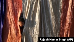 A girl living on the roadside looks out from her makeshift home during a lockdown to control the spread of the coronavirus in Prayagraj, India, on March 25. 