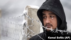 Një migrant qëndron pranë një gardhi në kampin Lipa të Bosnjes.