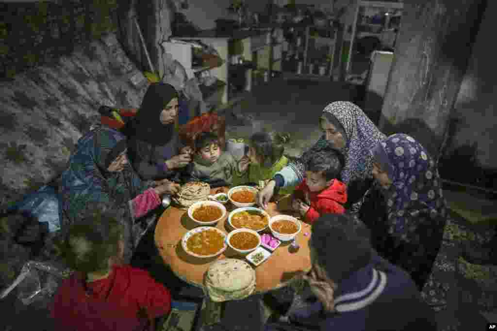 Fatima Al-Absi, majtas, duke ngrënë iftar, shujta pas agjërimit, me vajzën dhe nipërit e saj në ditën e parë të Ramazanit në apartamentin e tyre të dëmtuar në Xhabalia, në veri të Rripit të Gazës, të shtunën, më 1 mars 2025.