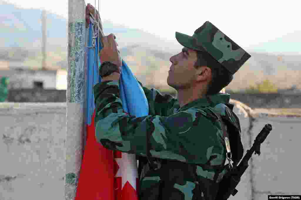 Un soldat azer arborează drapelul țării sale, în timpul unei ceremonii din satul Mincivan, cucerit recent în luptele cu forțele armene.
