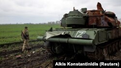 Український військовослужбовець проходить повз знищену російську самохідну зенітну установку, позначену літерою «Z», у селі Гусарівка на Харківщині, 14 квітня 2022 року