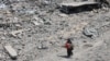 O femeie palestiniană cară crengi de lemn, în timp ce trece pe lângă dărâmăturile și ruinele din cartierul al-Tuffah al orașului Gaza, pe 14 august 2025.