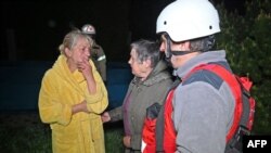 Salvatori ucraineni ajută locuitorii unui bloc rezidențial avariat în urma unui atac cu drone asupra Harkivului, în noaptea de 2-3 mai.
