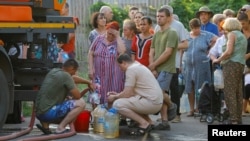 Locuitorii așteaptă la coadă pentru a lua apa livrată de o cisternă în Donețk, pe 29 iulie.
