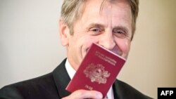 Renumitul balerin Mihail Barîșnikov arătând pașaportul leton primit după ce i s-a acordat cetățenia letonă la Riga, 27 aprilie 2017
