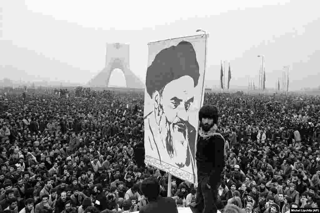 Demonstranti drže transparent s likom progranog islamskog vođe ajatolaha Homeinija dok se masa ljudi na ulicama u Teheranu povećava. Ove demonstracije od 10. decembra 1978. desile su se pored spomenika Šajah koji je izgrađen kako bi ovjekovječio vladavinu i moć monarha.&nbsp;&nbsp;&nbsp;&nbsp;&nbsp;