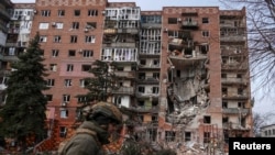 Një ushtar ukrainas kalon pranë një ndërtesëe banimi të dëmtuar nga sulmet ruse në qytetin e vijës së frontit, Pokrovsk, Ukrainë, më 6 mars.
