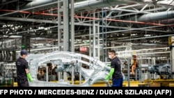 A Mercedes kecskeméti gyárában egy autó vázát mozgatják munkások 2020. március 24-én