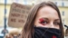 Žena na protestima u Varšavi nosi masku s usvojenim simbolom crvene munje (28. oktobar 2020.)