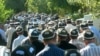 Мужчины в национальной тюбетейке, участвующие в похоронной процессии. 