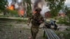 Un polițist din apărarea teritorială ucraineană pe fundalul unei clădiri lovite de o bombă rusească la Vovciansk, pe 11 mai 2024.