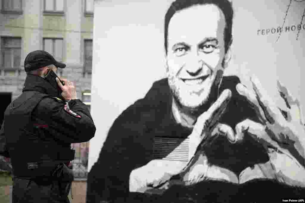 Telefonon egyeztet egy rendőr a Navalnijt ábrázoló graffiti előtt.