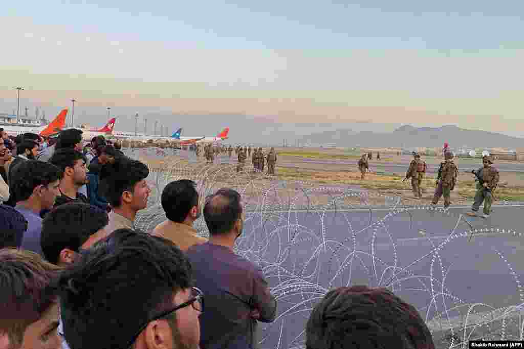 Afghan crowds gather at the airport as U.S. soldiers stand guard. 