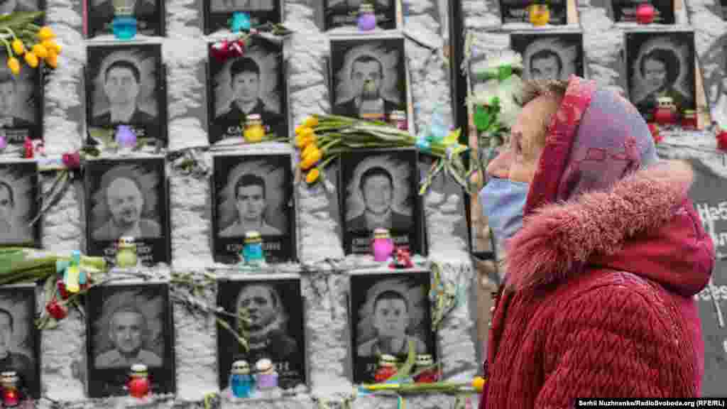 Seara de 18 februarie 2021, în fața monumentului din Kiev dedicat martirilor represaliilor din timpul Euromaidanului (Cei o sută de martiri). O femeie aduce onoruri celor 104 persoane ucise în timpul demonstrațiilor anti-guvernamentale din 2014&nbsp; 